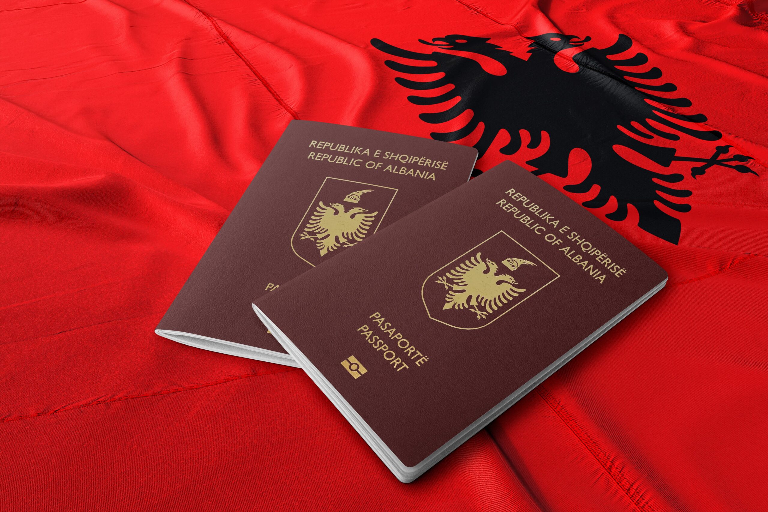 two albanian passports on a red albanian flag